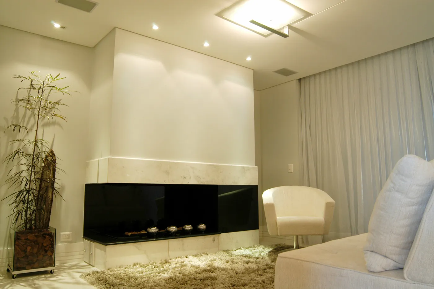 Sala residencial com lareira, sanca em gesso e iluminação indireta