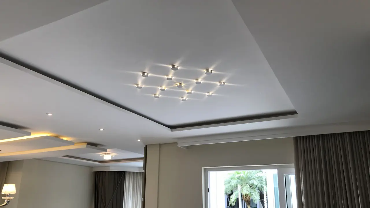Sala de estar com forro rebaixado, sanca iluminada e luminárias embutidas, executados pela Gesso Camargo