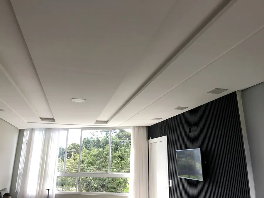 Sala com forro rebaixado e paredes pintadas, parede de destaque em ripado escuro
